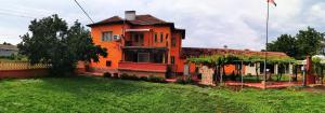 an orange house on a green field with a yard at Къща за гости и приятели Селановска среща in Selanovtsi