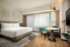 上海市にあるHoliday Inn Shanghai Nanjing Road, an IHG Hotelのベッド、テーブル、椅子が備わるホテルルームです。