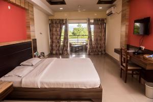 um quarto com uma cama, uma secretária e uma televisão em Hotel Aatreyee em Dibrugarh