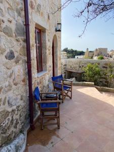 two blue chairs sitting outside of a stone building at La Perla de Maroulas in Maroulás