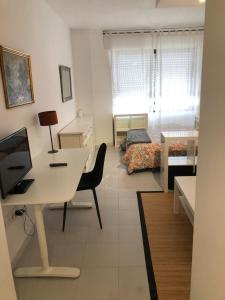 1 dormitorio y sala de estar con escritorio. en Resitur Apto 731, en Sevilla