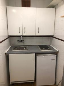 a small kitchen with white cabinets and a sink at Resitur Apto 731 in Seville
