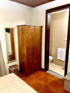 a bedroom with a wooden cabinet and a bathroom at Ninho das Cagarras in Santo Amaro