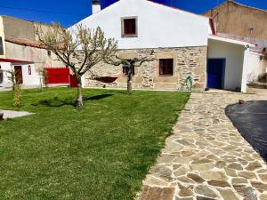a stone house with a green lawn in front of it at Casadaldeiadalmofala in Almofala
