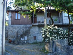 a building with a door and a tree with flowers at Casa do Faroca in Vieira do Minho