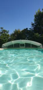 una piscina de agua con un edificio al fondo en Gîte "Dans les Airs", avec piscine chauffée et parking, en La Roche-sur-Yon