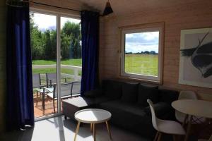 ein Wohnzimmer mit einer Couch und einem Tisch und Fenstern in der Unterkunft Zaciszne Gąski - domki letniskowe in Gąski