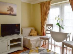 un salon avec une télévision et un canapé dans l'établissement 1-Bed Cottage on Coastal Pathway in South Wales, à Gileston