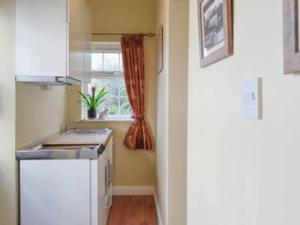 uma pequena cozinha com um lavatório e uma janela em 1-Bed Cottage on Coastal Pathway in South Wales em Gileston