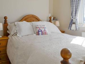 una camera da letto con un grande letto con lenzuola e cuscini bianchi di 1-Bed Cottage on Coastal Pathway in South Wales a Gileston