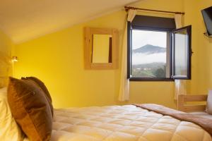 Dormitorio amarillo con cama y ventana en La Casona de Cardes en Cangas de Onís