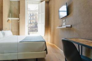 a bedroom with a bed and a desk and a tv at Cosmopolitan Boutique Rambla in Barcelona