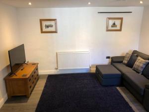 a living room with a couch and a tv at The Grooms Cottage in Llanrug