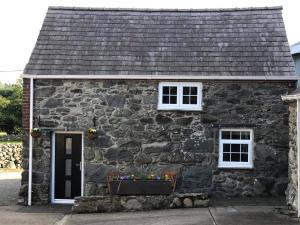 una casa de piedra con una caja de flores delante de ella en The Grooms Cottage en Llanrug