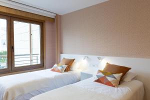 dwa łóżka w pokoju z oknem w obiekcie P18 Villalia Apartamento en la Isla de la Toja w mieście Isla de la Toja