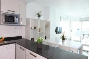 a kitchen with white cabinets and a black counter top at Rentyplus Mar Azul MangaNorte in La Manga del Mar Menor