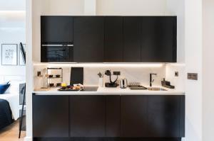 cocina con armarios negros y encimera blanca en BILBAO URBAN by STAYNN APARTMENTS, en Bilbao