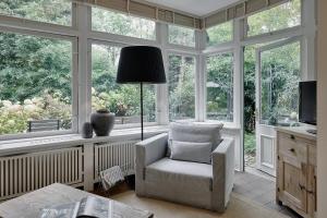 ein Wohnzimmer mit einem Stuhl vor den Fenstern in der Unterkunft Landhaus Flottbek Boutique Hotel in Hamburg