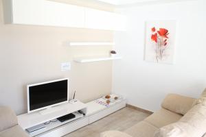 a white living room with a flat screen tv at Villa BETTY in Cala en Blanes