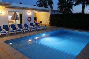 a swimming pool with chairs and a house at Villa BETTY in Cala en Blanes