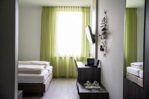 Habitación con 2 camas y ventana con cortinas verdes. en eee Hotel Graz, en Neupirka