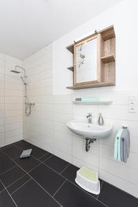 a white bathroom with a sink and a mirror at Ferienwohnungen im Haus Meeresleuchten in Neuharlingersiel +32 photos