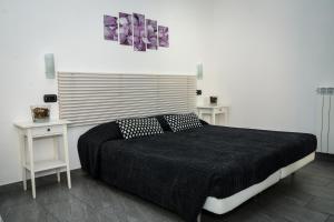 sypialnia z czarnym łóżkiem i dwoma białymi stołami w obiekcie Affittacamere Delfo w Pizie