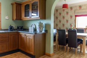 uma cozinha com armários de madeira e uma mesa com cadeiras em Ar Dachaigh, North Uist em Paible