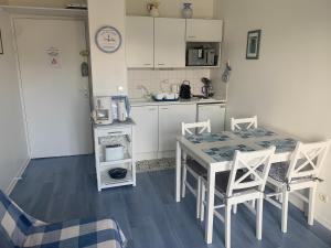 a kitchen with a table and chairs in a room at Appartement Cabourg bord de mer in Cabourg