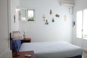 a white bedroom with a bed and a window at Agkeria great feeling house in Kampos Paros