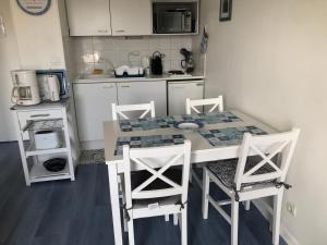 a kitchen with a table and four chairs in it at Appartement Cabourg bord de mer in Cabourg