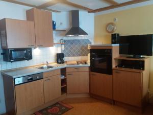 a kitchen with wooden cabinets and a sink and a microwave at Ferienwohnung Dopfer in Eisenberg