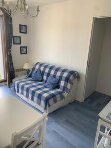 a couch in a living room with a plaid blanket at Appartement Cabourg bord de mer in Cabourg
