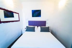 a bedroom with a large white bed with a purple headboard at Etna Suite Group in Catania