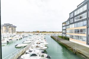 a group of boats docked in a marina next to a building at Le Gréement - Appt vue sur le port in Courseulles-sur-Mer