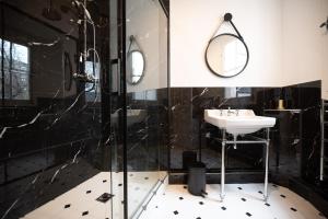y baño blanco y negro con lavabo y ducha. en Luxury flat Victor Hugo en París