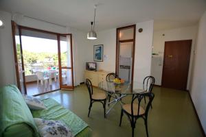 un soggiorno con tavolo e sedie e una cucina di Lignano Riviera economico con piscina a Lignano Sabbiadoro