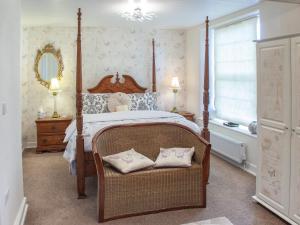 a bedroom with a canopy bed with a chair and a window at Court Prior Boutique B&B and Apartment in Torquay