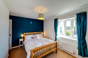1 dormitorio con 1 cama grande y pared azul en Kittiwake Cottage Camber Sands, en Camber