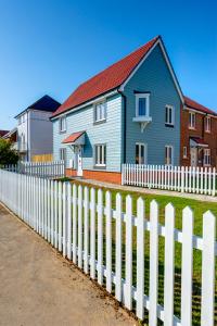 a blue house behind a white picket fence at Kittiwake Cottage Camber Sands in Camber