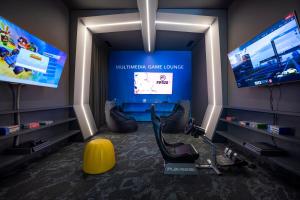 a living room with two large screens and a yellow chair at Valamar Diamant Hotel in Poreč