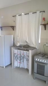 una pequeña cocina con fogones y cortinas blancas en Kitnet 1,Vista fantastica, en Cabo de Santo Agostinho