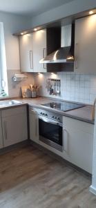 uma cozinha com armários brancos e um forno com placa de fogão em Haus Strandflieder em Greetsiel