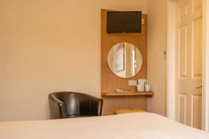 a bedroom with a bed and a mirror and a chair at Briscoe Lodge in Windermere