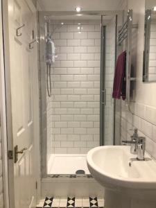 ein weißes Bad mit einer Dusche und einem Waschbecken in der Unterkunft Briscoe Lodge in Windermere