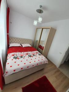 Schlafzimmer mit einem Bett mit einer roten Bettdecke und einem Spiegel in der Unterkunft Apartament 3 camere militari residence in Roşu