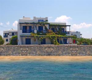 a house on a stone wall next to the water at Studios Vagos 2 in Agios Prokopios