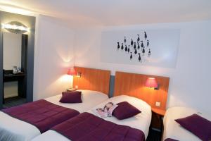 two beds in a hotel room with a girl laying on them at Hotel inn Dijon-Quetigny in Quétigny +16 photos