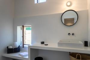 a white bathroom with a mirror and a sink at Le Domaine du Castellas in Sivergues