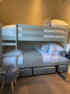 a bedroom with two bunk beds and a stool at The Fuzzy Duck in Newbold on Stour